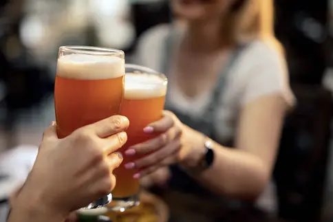 photo of couple toasting with beer in a bar