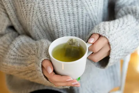 photo of woman holding cup of green tea