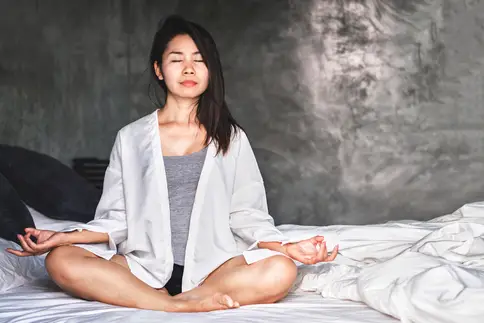 photo of woman meditating on bed