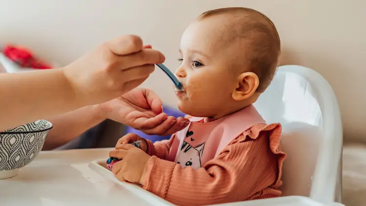 photo of baby getting fed in high chair