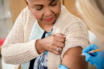 nurse giving vaccination to senior woman