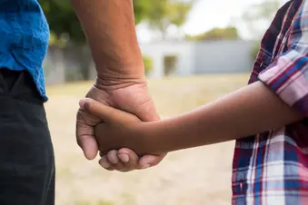 Parent holding child's hand outdoors