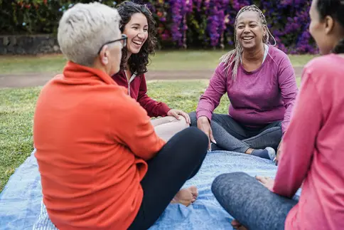 photo of women sitting on a blanket in a park
