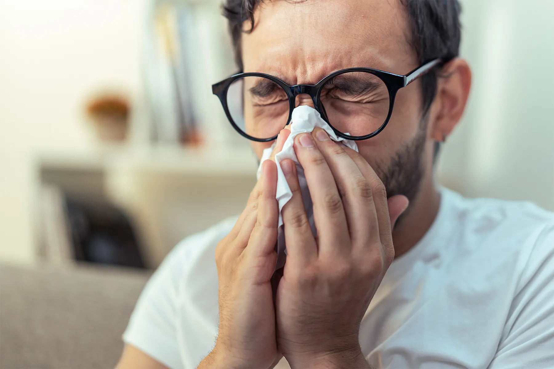 photo of Young man with glasses sneezing