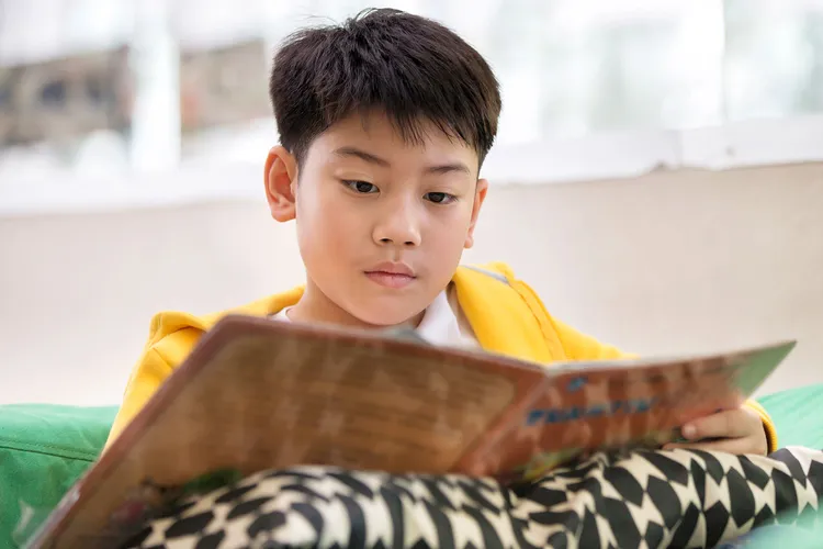 photo of Asian child reading a book.