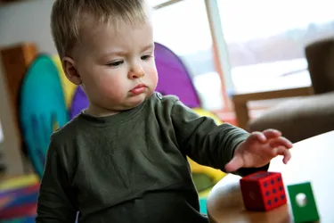 Motor skill developmental delays may be related to problems with gross motor skills, such as crawling or walking, or fine motor skills, such as using fingers to grasp a spoon. By 3 to 4 months of age, most children can reach for, grasp, or hold objects. (Photo Credit: iStock/Getty Images)