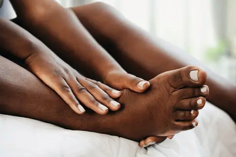 photo of woman massaging her foot