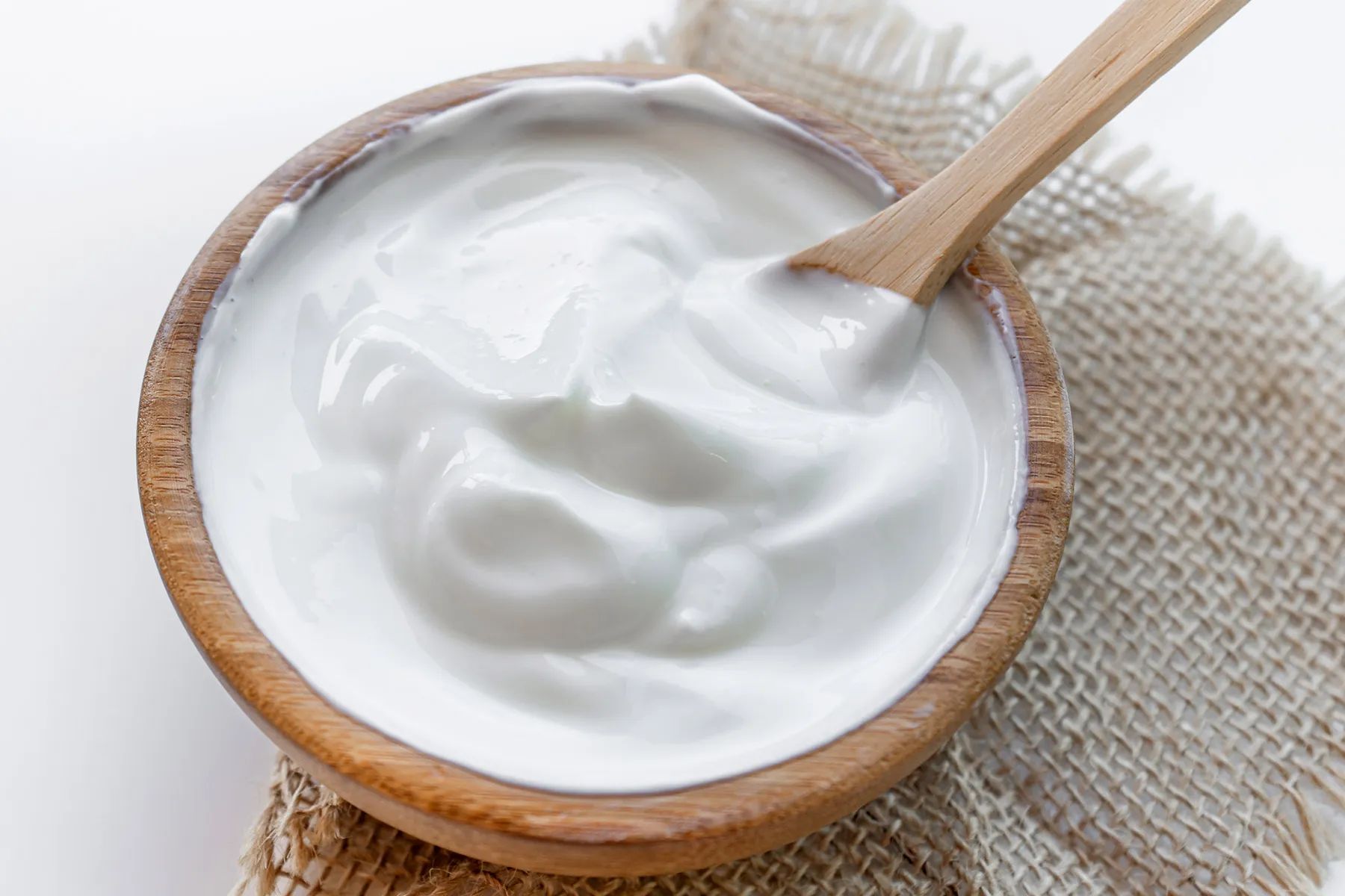 Wooden bowl of thick Greek yogurt with wooden spoon