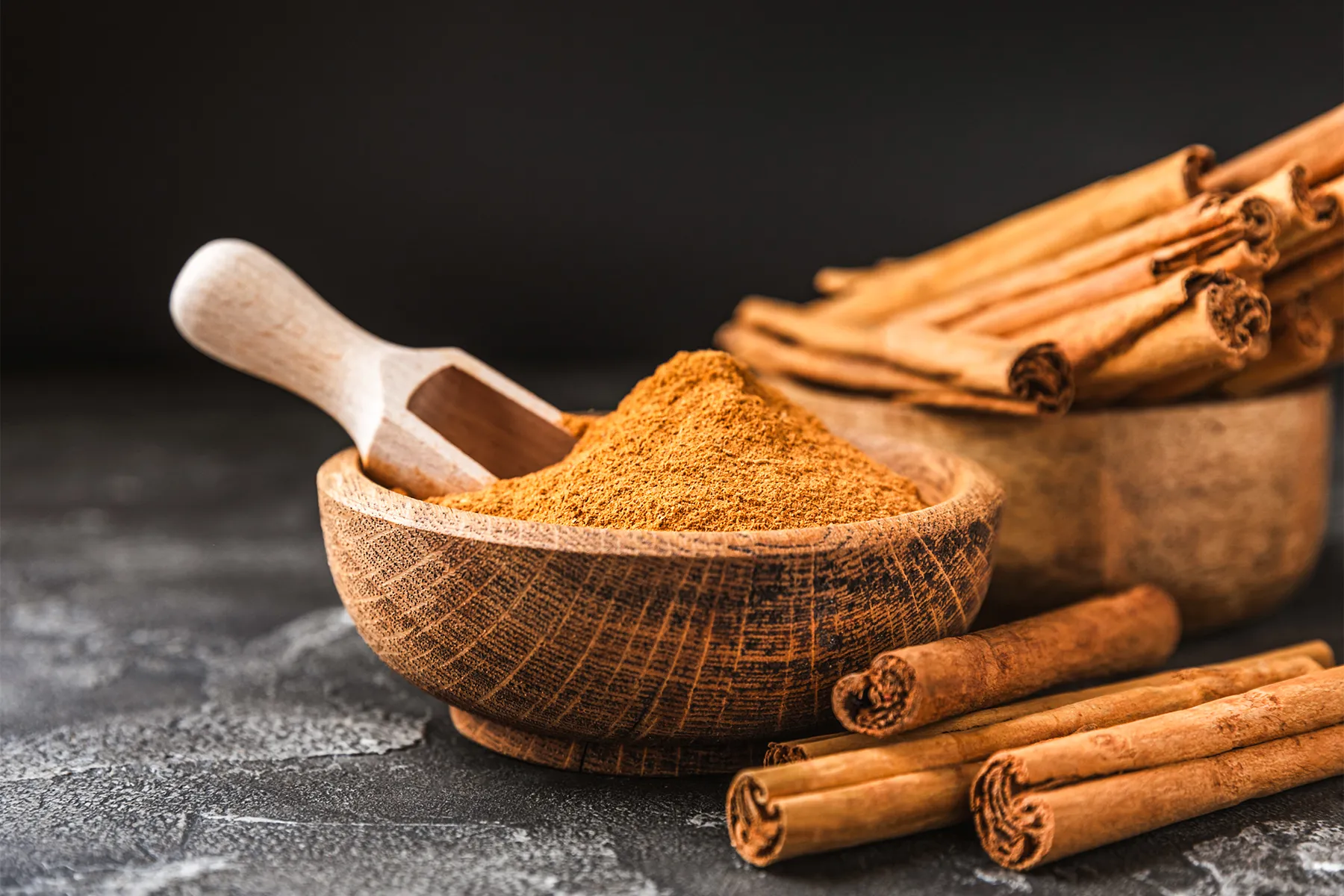 Cinnamon sticks and ground cinnamon in wooden bowls