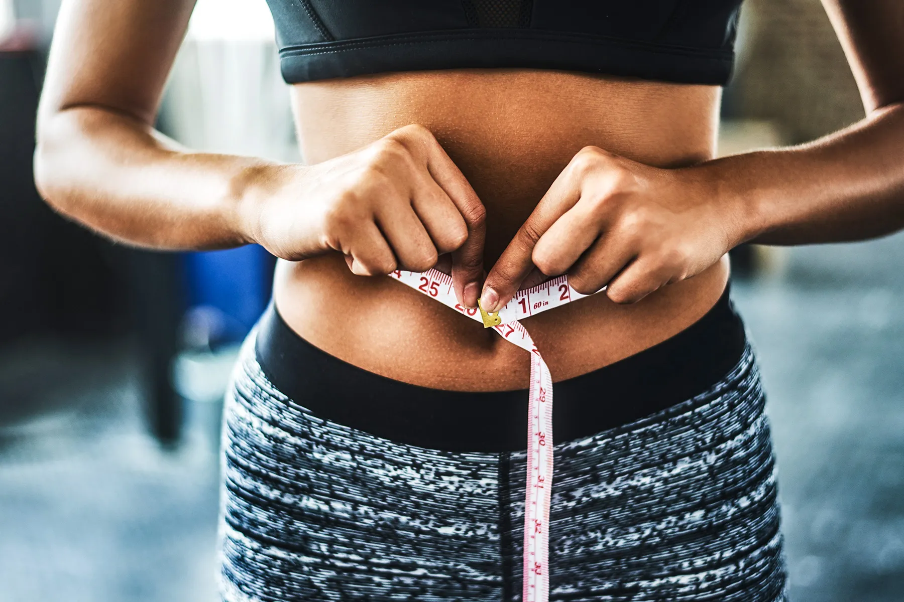 photo of  young woman measuring her waist