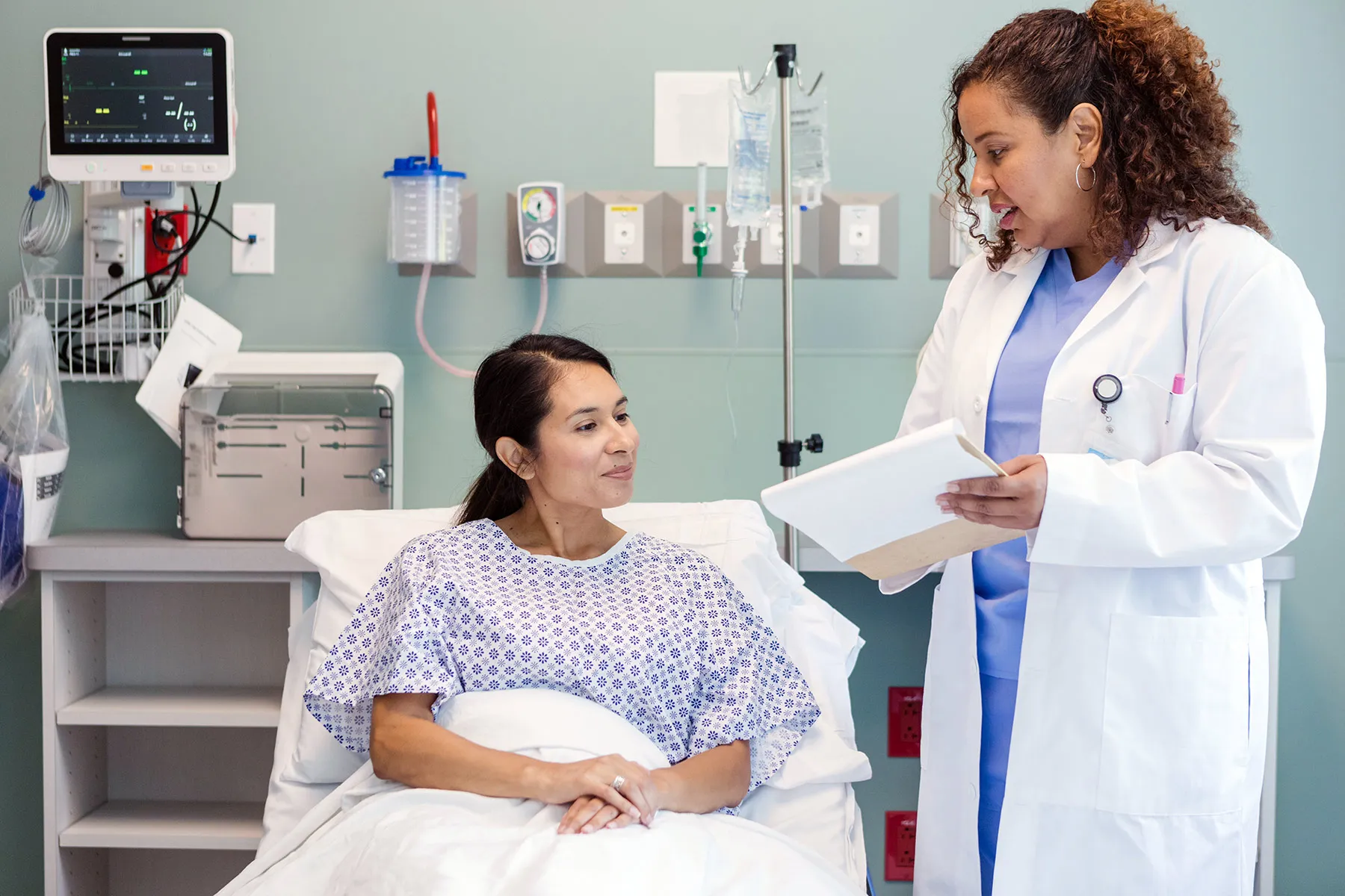 photo of doctor talking with woman in hospital bed