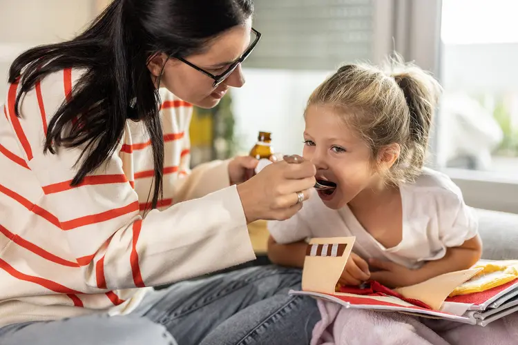 photo of mother giving liquid medicine to sick daughter
