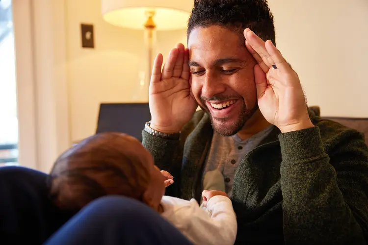 photo of father playing peekaboo with baby boy