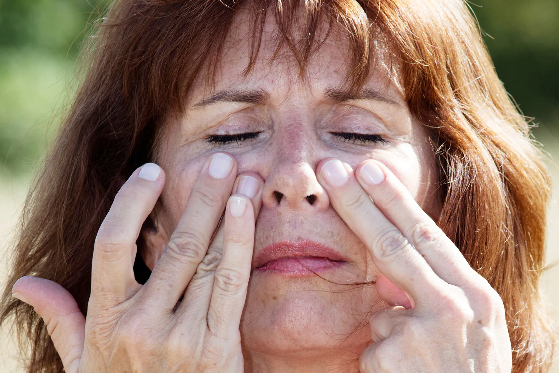 photo of woman massaging sinuses