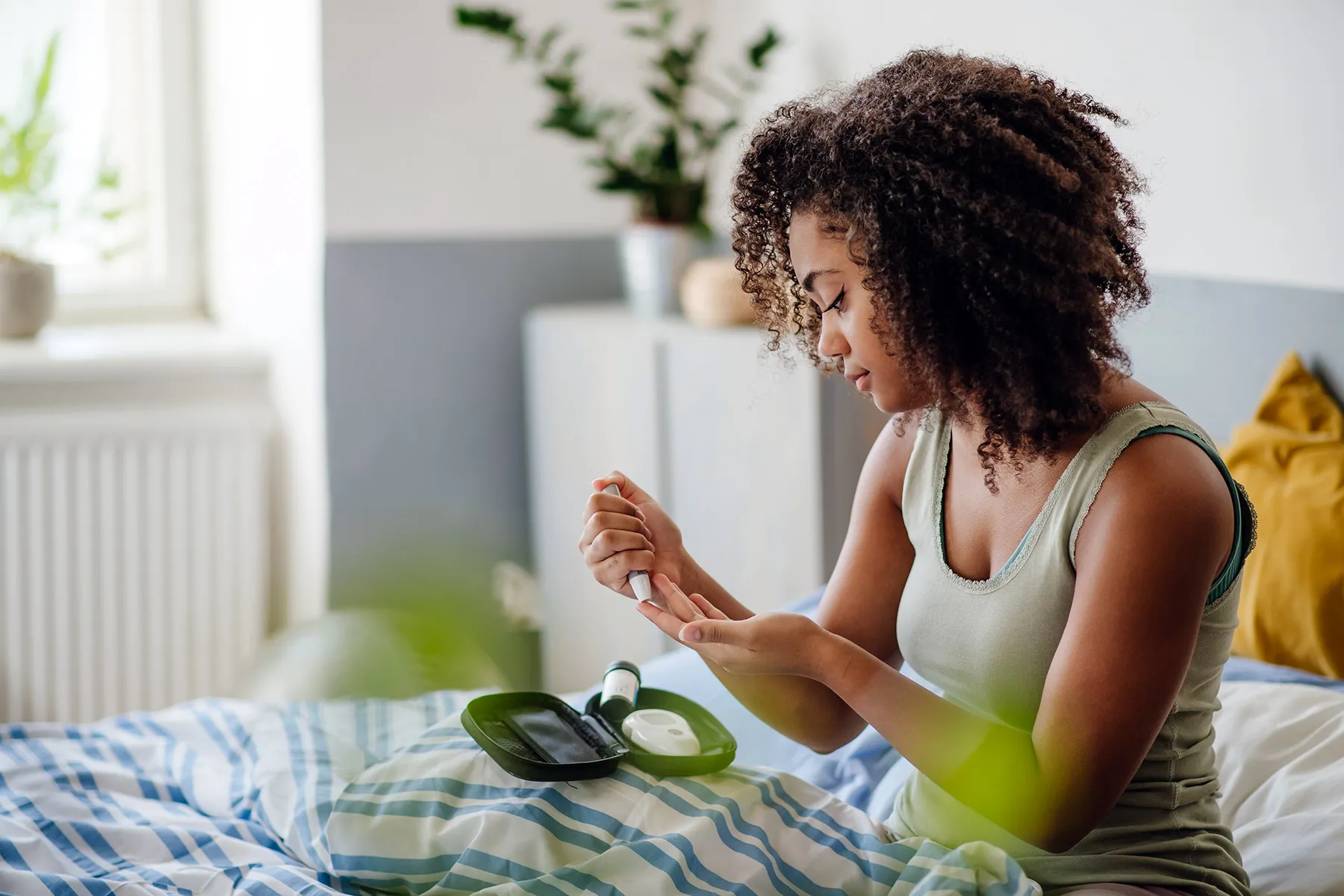 photo of young woman testing blood sugar in bed