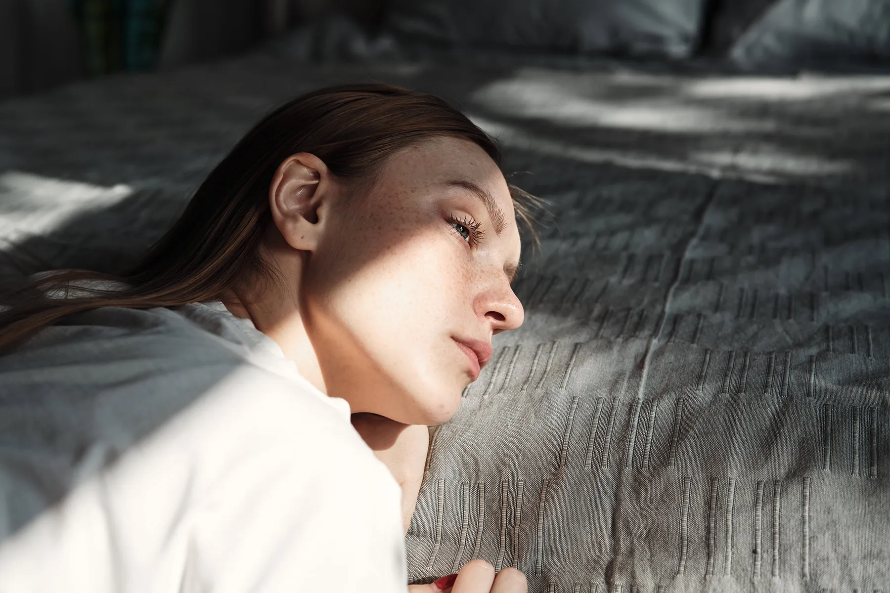 photo of depressed woman resting head on bed