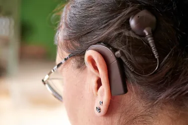 A cochlear implant has an external processor that looks like a hearing aid with a magnetic disk attached. The magnet connects to a receiver under your scalp. (Photo Credit: Moment/Getty Images)