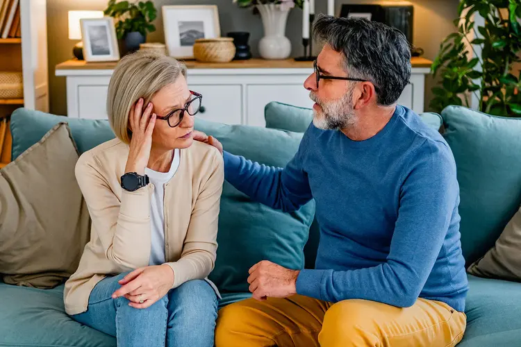 photo of man comforting woman on couch