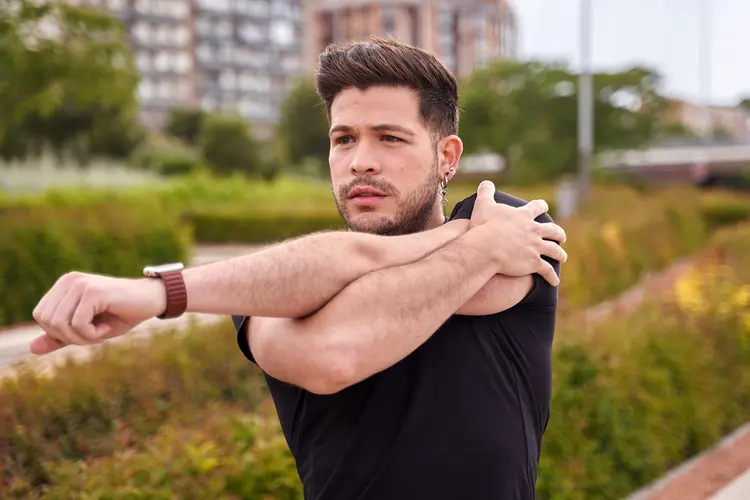 photo of young man stretching shoulder
