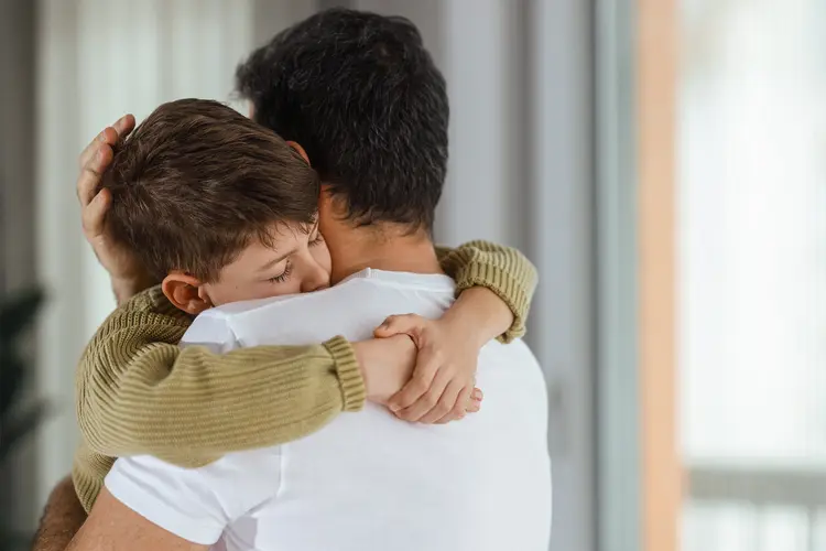photo of boy and his father hugging 