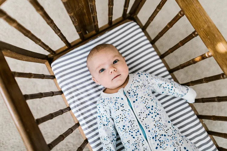 photo of Baby laying in a wooden cradle