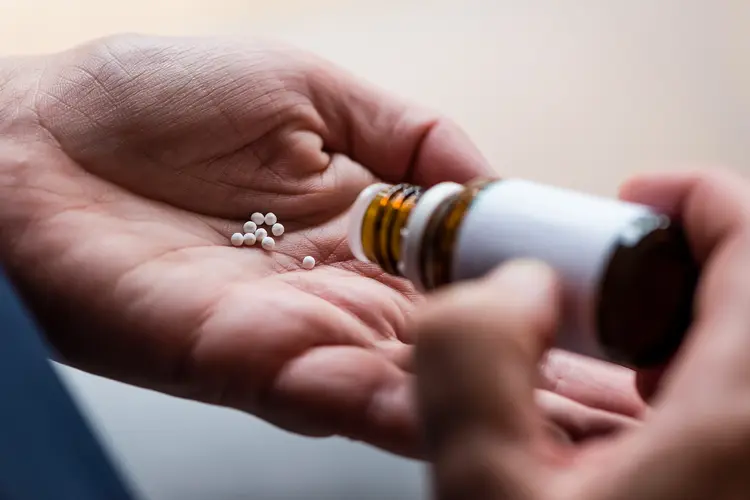 Photo of woman is pouring homeopathic pills out of a bottle into her open palm