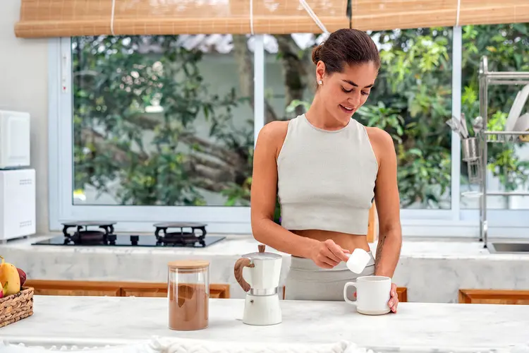 photo of woman adding protein powder to cup of coffee