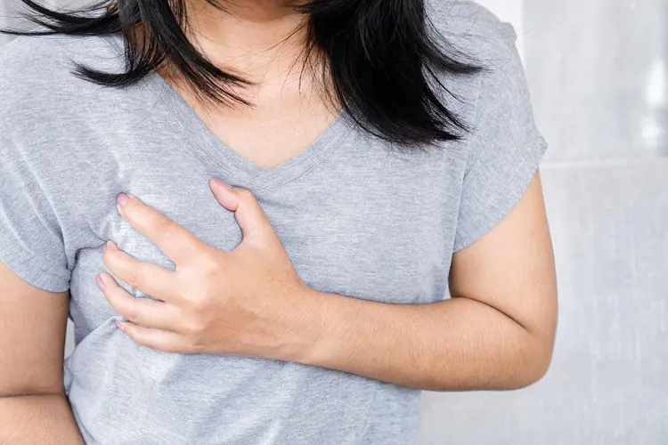 photo of woman holding breast in pain