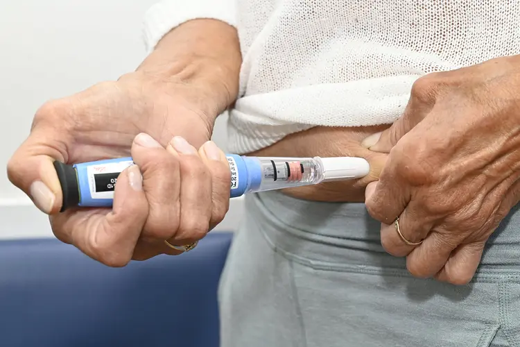 photo of man using a prefilled pen device to inject medicine into his abdomen