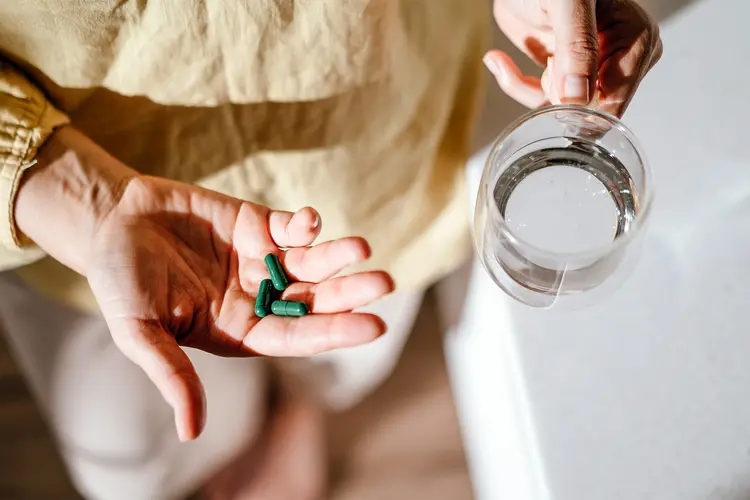 photo of woman with green pills in her hand.