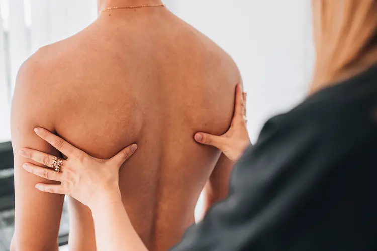 photo of physiotherapist examining man's back; scapular dyskinesis