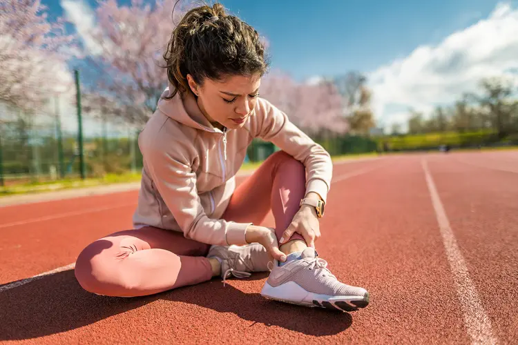 photo of young woman holding sprained ankle