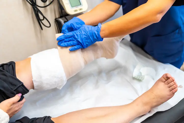 photo of nurse wrapping patient's wounded leg