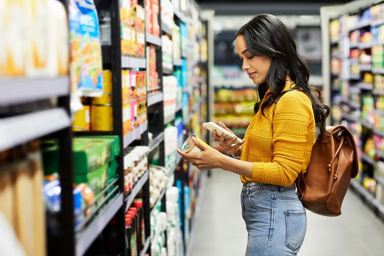 photo of young woman reading food label in grocery store