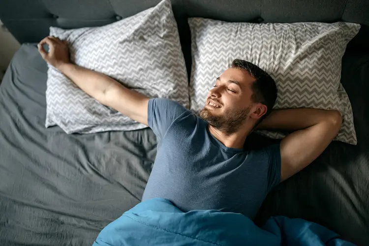 Photo of man waking up in bed, representing the phenomenon of “morning wood”