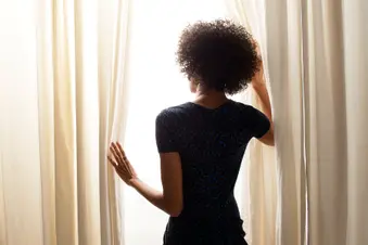 photo of woman opening curtain at window