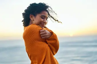 photo of woman embracing herself on beach