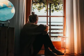 photo of woman looking out window at sunset
