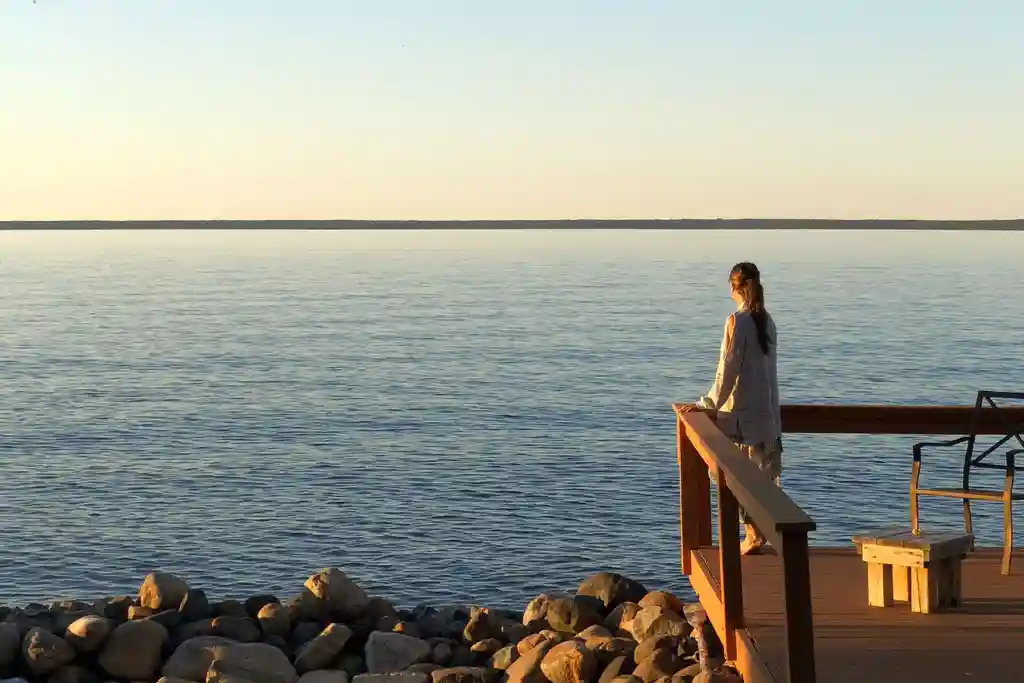 photo of woman looking at sunset and sea
