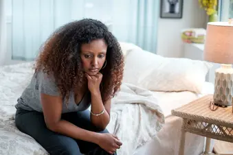 photo of sad woman sitting on bed