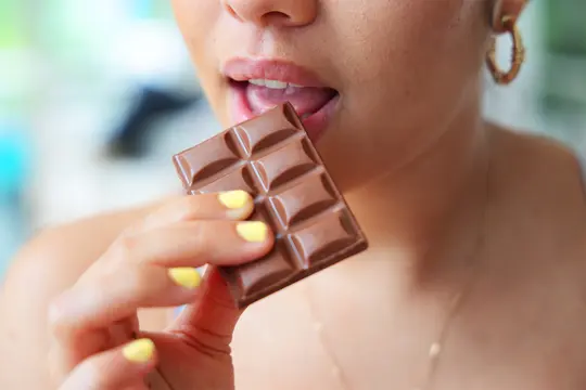 photo of woman taking bite of chocolate