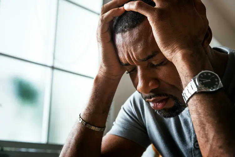 photo of man with migraine holding head in hands