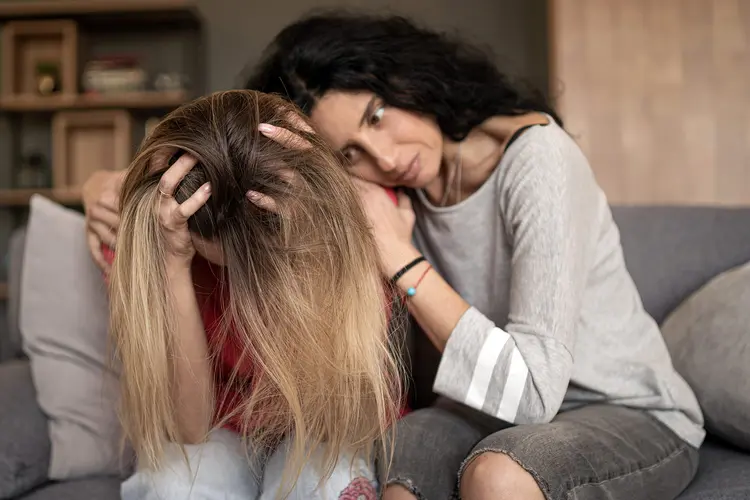 photo of woman comforting friend in pain