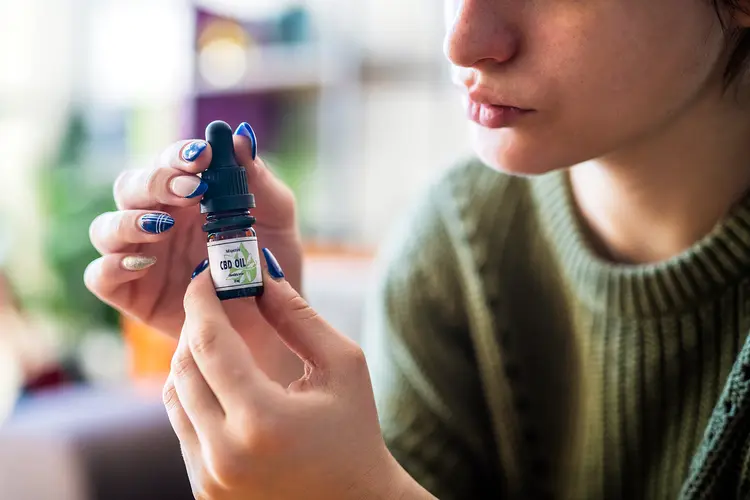 photo of young woman holding bottle of CBD oil