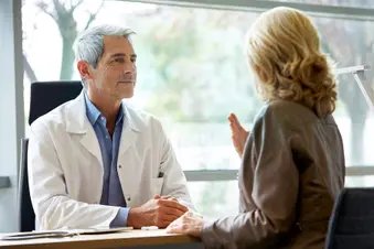 photo of doctor listening to female patient