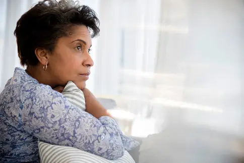 photo of pensive woman clutching pillow
