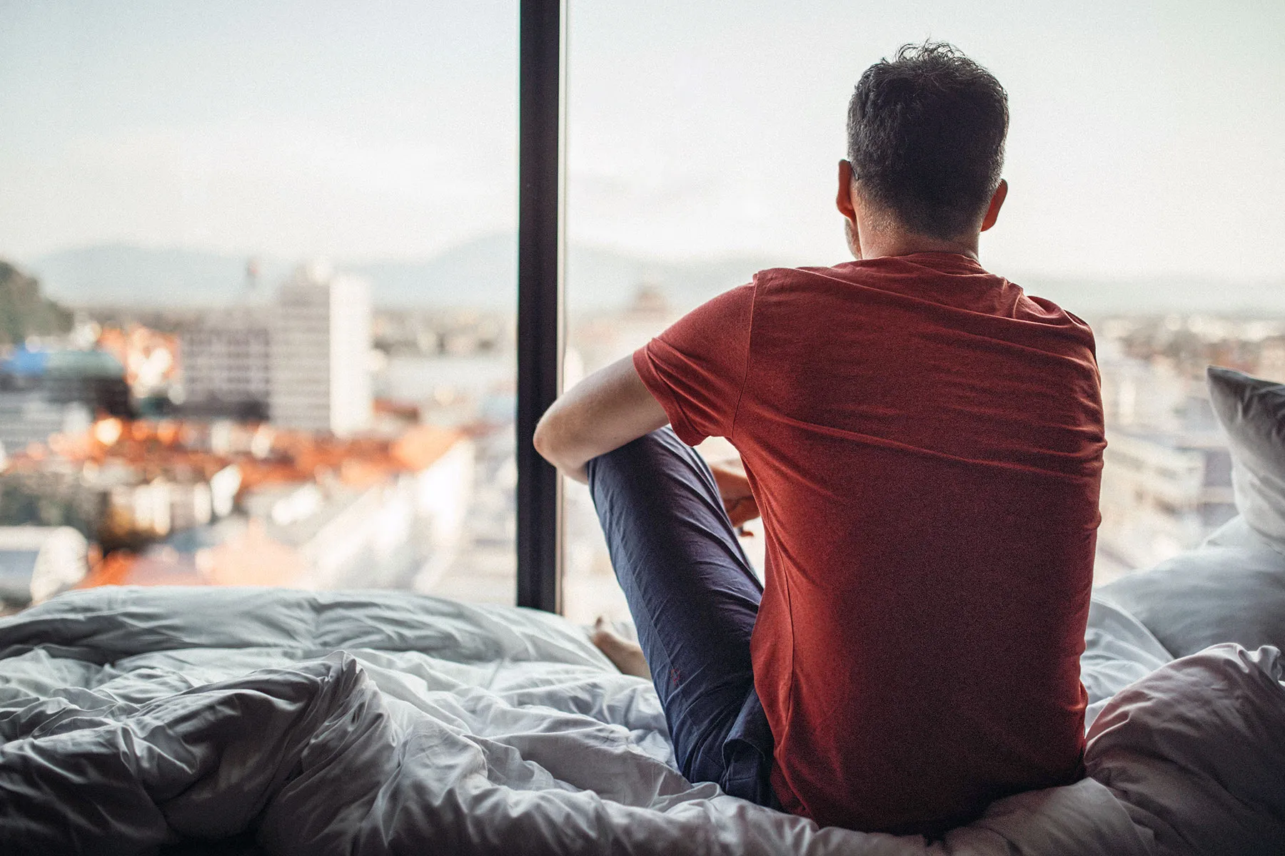 photo of man looking through window at city