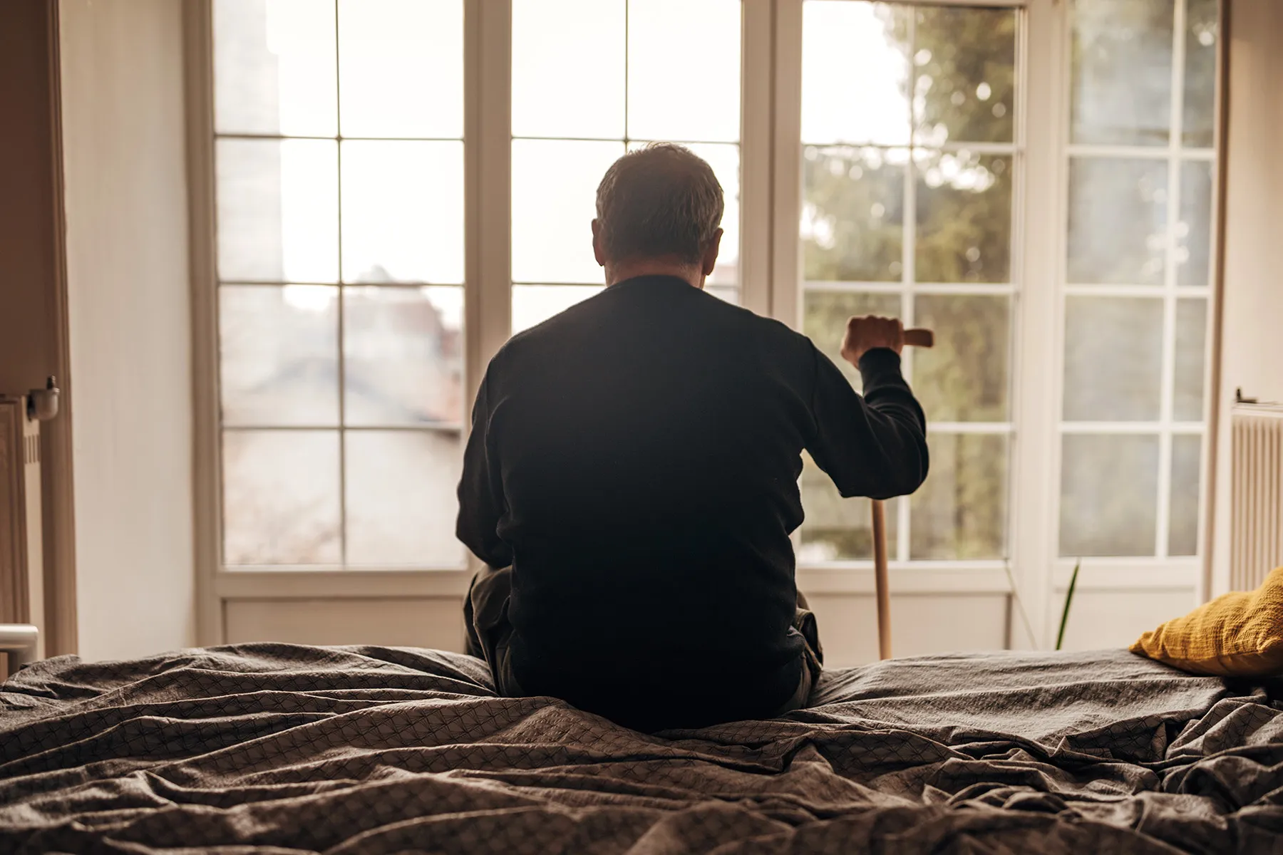 photo of senior man sitting on bed