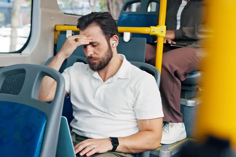 photo of man experiencing headache while riding on bus