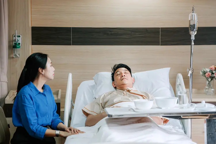 photo of female caregiver with partner lying in hospital bed